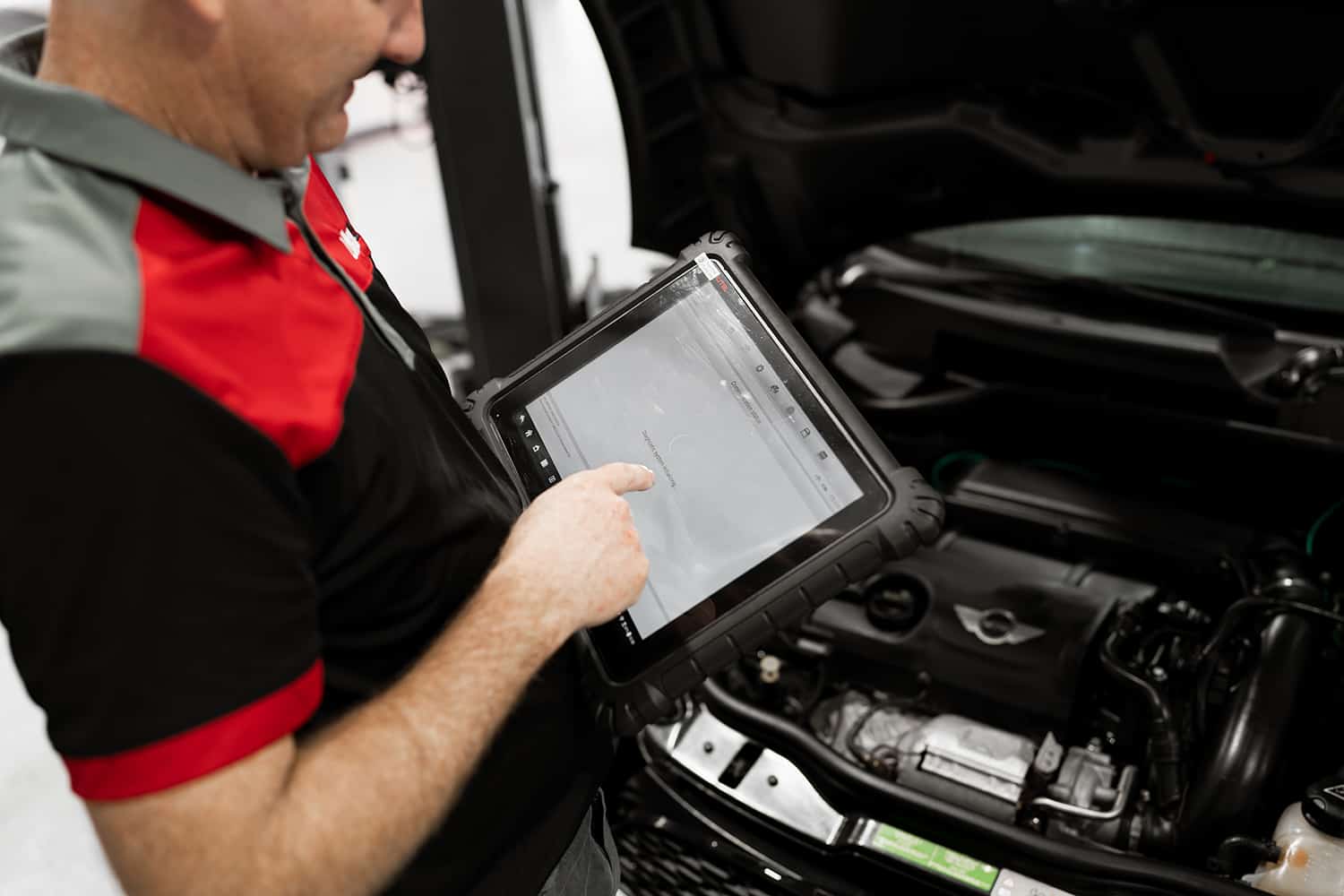 An expert car mechanic using technology for a car engine diagnostics