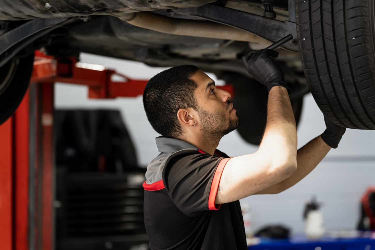 A car mechanic working on the underside of the car, doing a tyre replacement and engine diagnostics during a European Car Brake Repairs in Brisbane and Tyre Replacement & Fitting in Brisbane