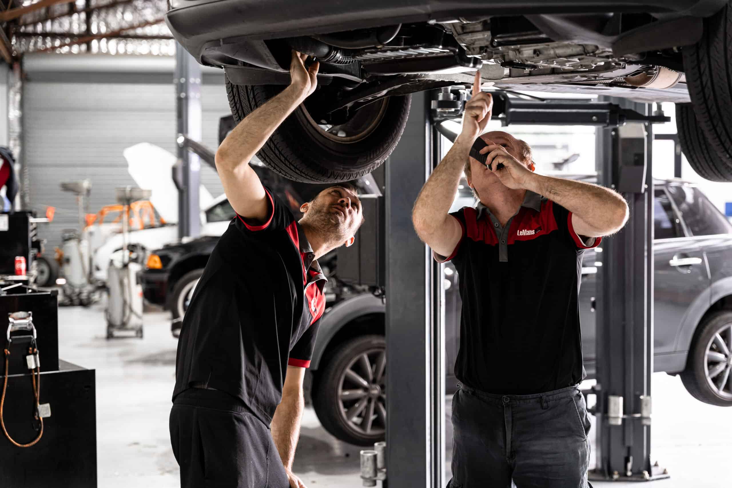 Car mechanics servicing a car thats raised up during a European Car Log Book Servicing