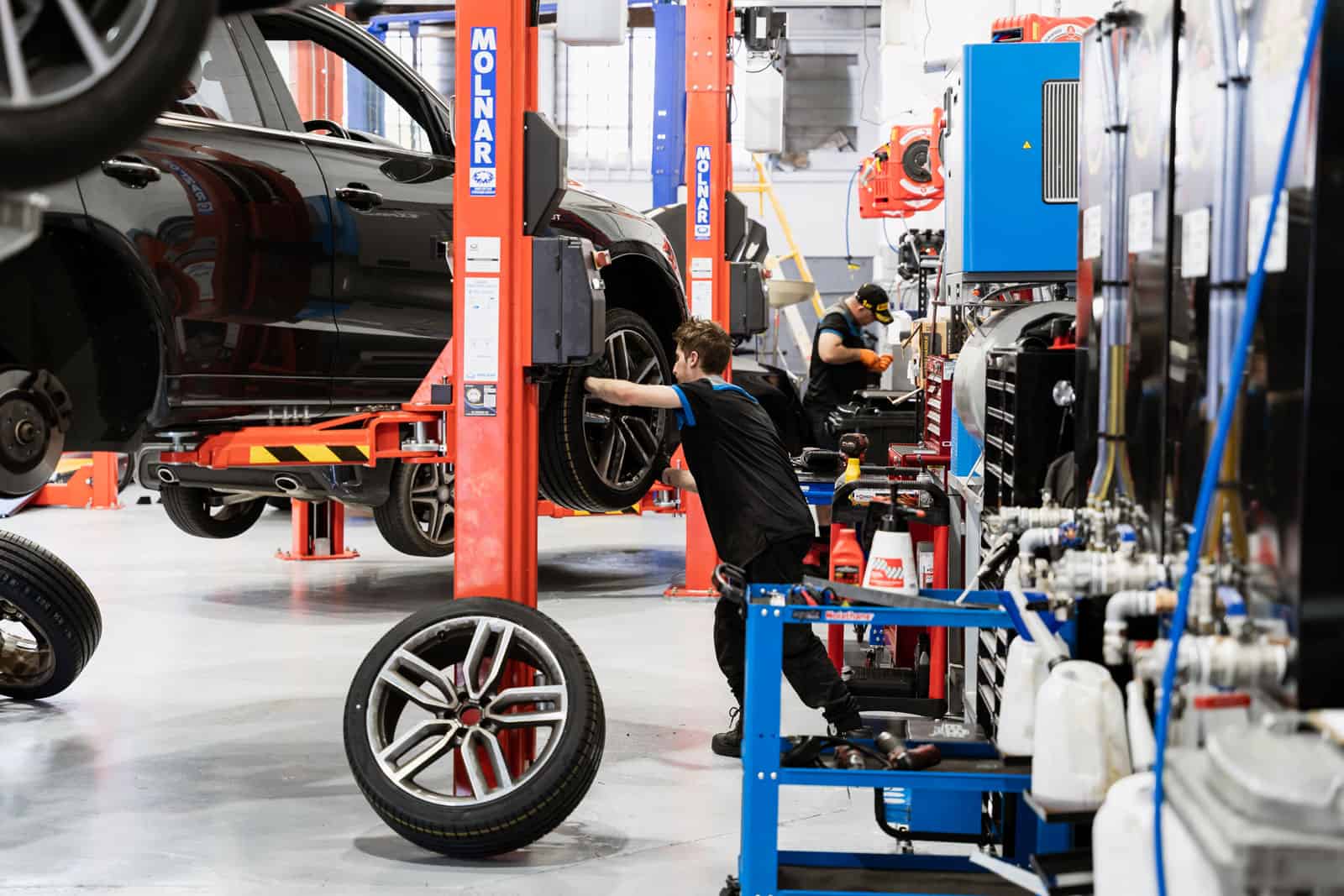 A mechanics workshop full of cars and car mechanics at work