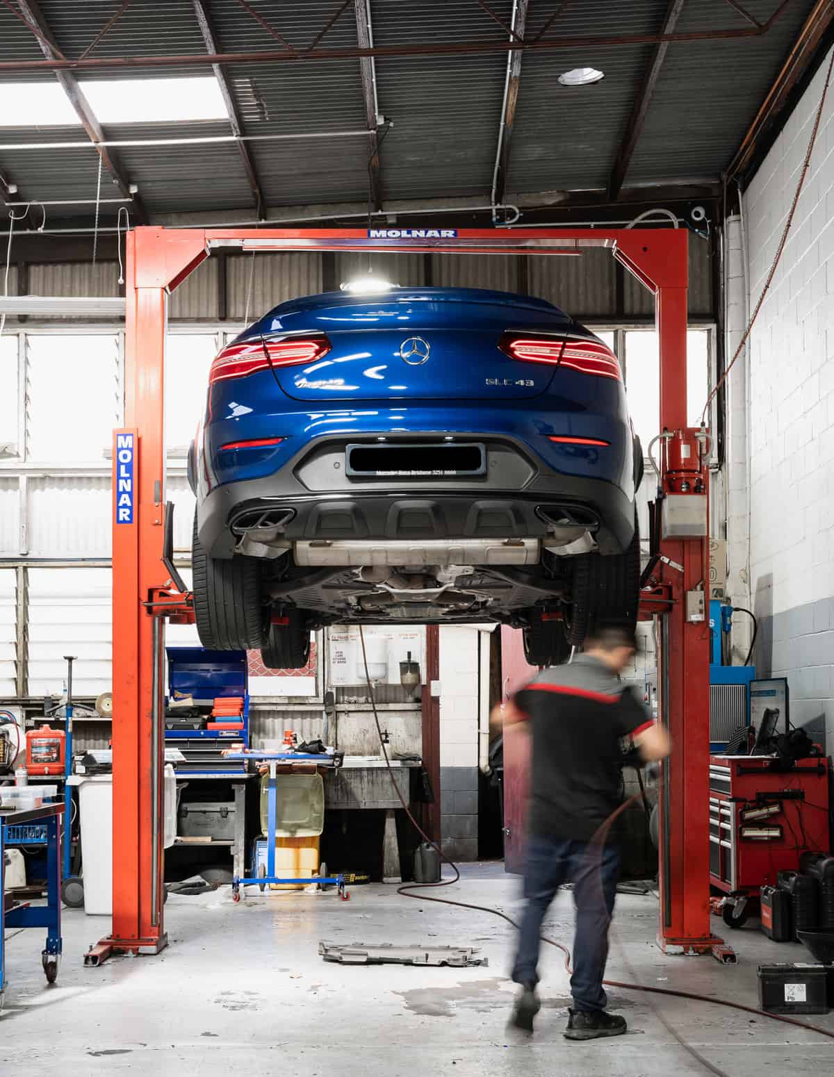 A blue Mercedes car raised up for an engine diagnostic