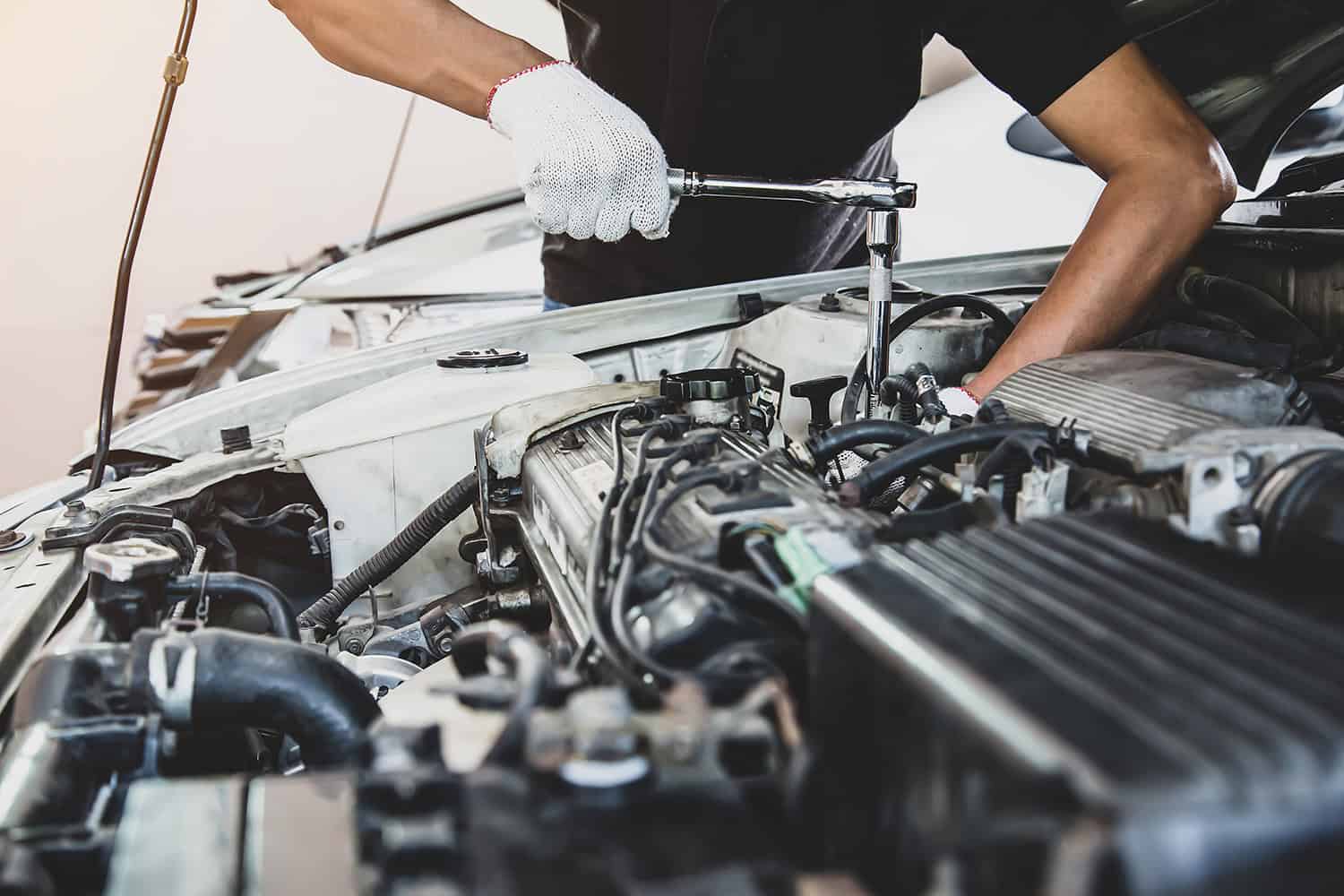 Close up of the hands of a mechanic using a wrench to repair a car engine